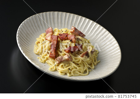 Carbonara with crispy thick-sliced bacon photographed against a black background 81753745