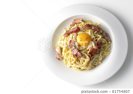 Aerial view of carbonara with egg yolk and crispy thick-sliced bacon on a white background Aerial view of carbonara with egg yolk and crispy thick-sliced bacon on a white background 81754807