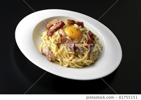 Carbonara with egg yolk and crispy thick-sliced bacon photographed against a black background Carbonara with egg yolk and crispy thick-sliced bacon photographed against a black background 81755151