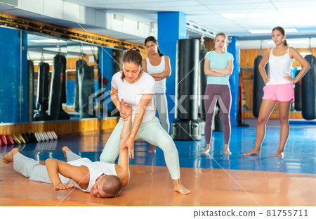 Young hispanic woman mastering hammerlock on male opponent in self defence training in gym 81755711