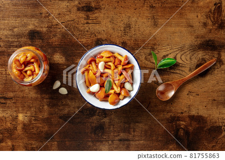 Pickled mushrooms in a jar, with garlic, and a bay leaf, overhead flat lay shot 81755863