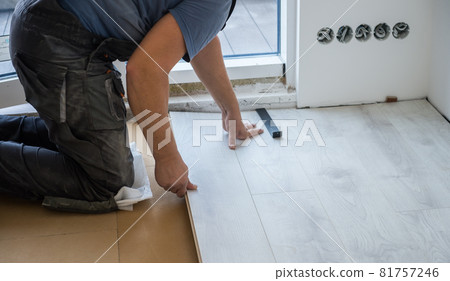 Man installing new white laminate White wooden floor and white walls. floor covering at home. renovation. Wood flooring Abstract. Man installing new white laminate White wooden floor and white walls. floor covering at home. renovation. Wood flooring Abstract. 81757246