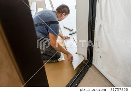 Man installing laminate flooring in new home indoor. Laying the floor. floor covering at home. renovation. Hammer and set of tools. Worker installing laminated wooden floor. closeup 81757266