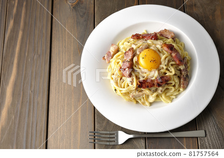 Carbonara with egg yolk and crispy thick-sliced bacon and a fork (top view) 81757564