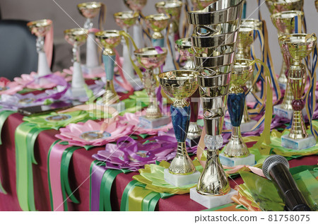 Various sports trophies, awards ribbons and a microphone on the table. Group of golden sports cups trophies on the table. Victory, champions, luck, success, sport. 81758075