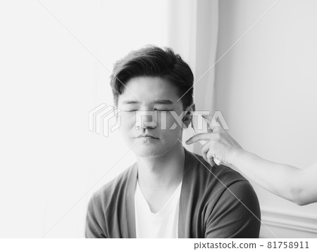 戴著外科口罩和使用耳溫計量體溫的亞洲年輕男子 戴著外科口罩和使用耳溫計量體溫的亞洲年輕男子 81758911
