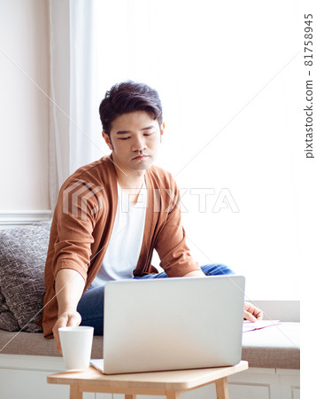 坐在筆記型電腦前面的的亞裔年輕人 81758945