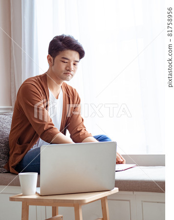 坐在筆記型電腦前面的的亞裔年輕人 81758956