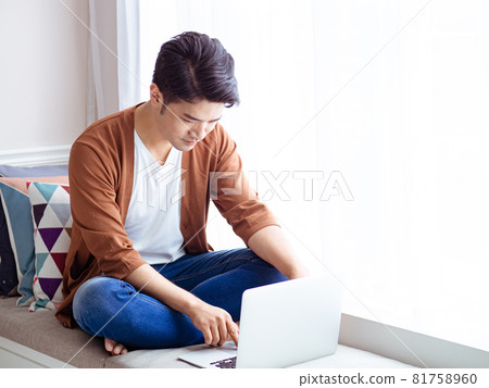 一個亞洲人寫的，他穿著不用的衣服，他用的是這本書和電腦。 81758960