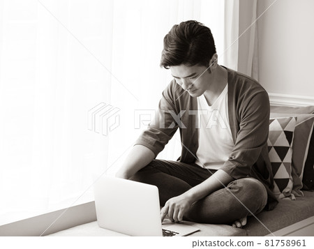 一個亞洲人寫的，他穿著不用的衣服，他用的是這本書和電腦。 81758961