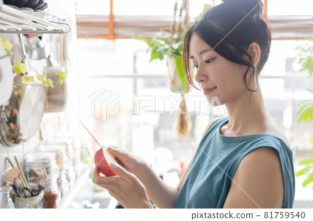 Young woman cutting an apple in the kitchen Young woman cutting an apple in the kitchen 81759540
