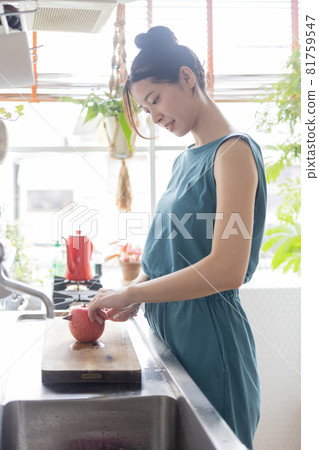 Young woman cutting an apple in the kitchen Young woman cutting an apple in the kitchen 81759547