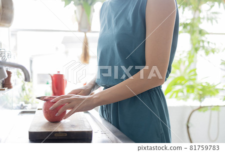 Young woman cutting an apple in the kitchen Young woman cutting an apple in the kitchen 81759783