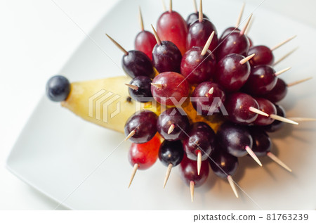 Fruit hedgehog, red grapes and juicy pear, creative way of serving fruit Fruit hedgehog, red grapes and juicy pear, creative way of serving fruit 81763239