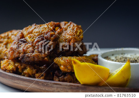 Delicious onion bhaji fritters served on wooden plate with white dip Delicious onion bhaji fritters served on wooden plate with white dip 81763510