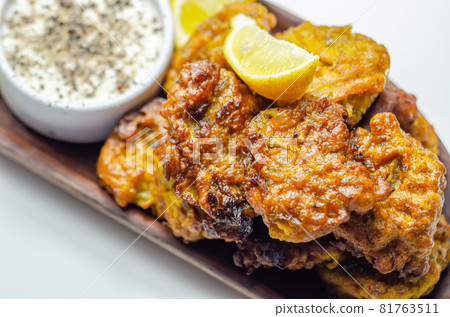 Delicious onion bhaji fritters served on wooden plate with white dip Delicious onion bhaji fritters served on wooden plate with white dip 81763511