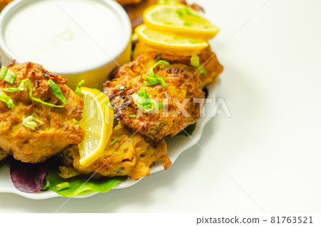 Delicious onion bhaji fritters served on ceramic plate with white dip Delicious onion bhaji fritters served on ceramic plate with white dip 81763521