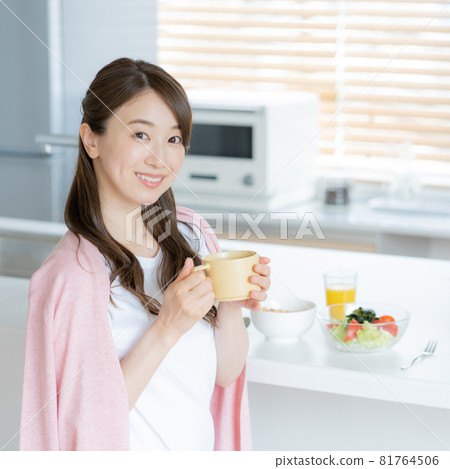 A young woman who turns around while eating breakfast in the dining kitchen Square 81764506