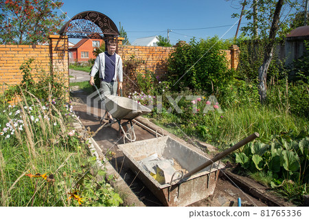A man unloads sand into a cement mixture for pouring a garden path 81765336