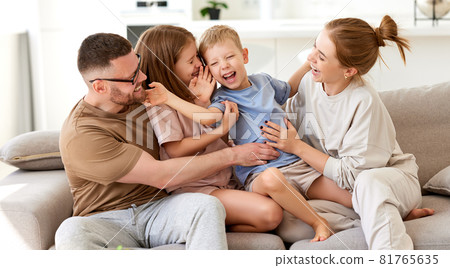 Happy beautiful family having fun and playing while relaxing on sofa in living room Happy beautiful family having fun and playing while relaxing on sofa in living room 81765635