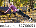 Young woman does push-up exercises in the park. Sports outside in autumn 81766051