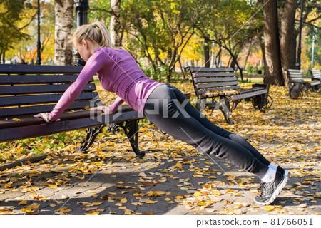 Young woman does push-up exercises in the park. Sports outside in autumn 81766051