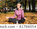 A young woman plays sports outside in an autumn park and listens to music with headphones 81766054