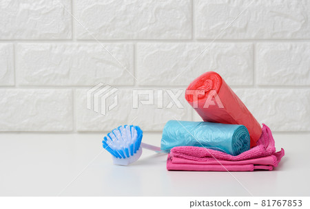 brush and stack of disposable plastic trash can bags 81767853