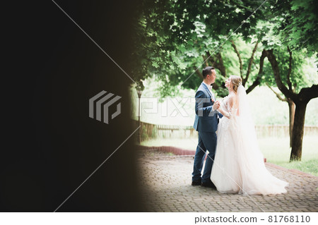 Beautiful bride and groom embracing and kissing on their wedding day outdoors Beautiful bride and groom embracing and kissing on their wedding day outdoors 81768110