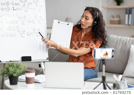 Female teacher explaining math online showing clipboard to laptop Female teacher explaining math online showing clipboard to laptop 81769278