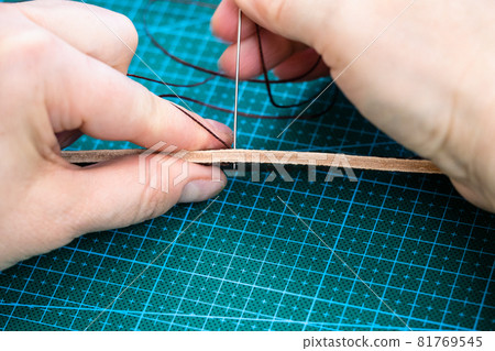 workshop of making the carved leather bag - craftsman sews the belt for leather handbag by needle with thread 81769545