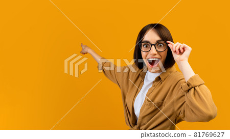Seasonal sale. Surprised lady pointing at empty space over yellow studio background, banner design, panorama Seasonal sale. Surprised lady pointing at empty space over yellow studio background, banner design, panorama 81769627