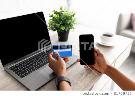 Closeup of black lady using cellphone, laptop and credit card to shop online, mockup for shopping app or website Closeup of black lady using cellphone, laptop and credit card to shop online, mockup for shopping app or website 81769735