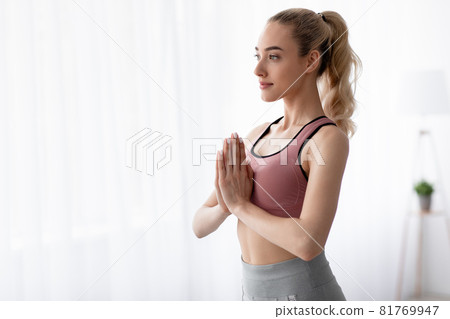 Calm european pretty millennial blonde lady practicing yoga at home, on large window background Calm european pretty millennial blonde lady practicing yoga at home, on large window background 81769947