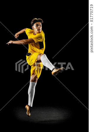 Full-length portrait of young man, football player training isolated on black background. 81770719
