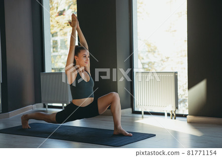 Young slim sportive woman in sportswear doing yoga exercise on gray mat at yoga sport center. Concept of healthy lifestyle, wellbeing, mental health 81771154