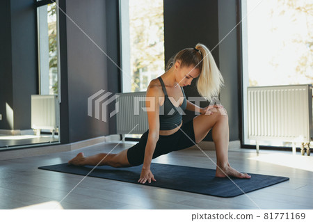 Young slim sportive woman in sportswear doing yoga exercise on gray mat at yoga sport center. Concept of healthy lifestyle, wellbeing, mental health 81771169