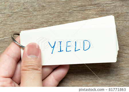 Man hold the flash card with handwriting word yield on wood background 81771863