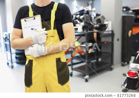 Auto mechanic locksmith in yellow uniform stands in car repair shop closeup Auto mechanic locksmith in yellow uniform stands in car repair shop closeup 81773268