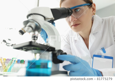 Portrait of female scientist looking through microscope in laboratory 81773279