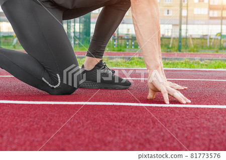 Athlete on the starting line of a stadium track preparing for a run. Athlete on the starting line of a stadium track preparing for a run. 81773576