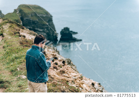 Man is standing on edge of the cliff on Irish sea 81775513
