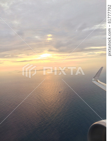 一架飛機在天空中撲騰的空拍影像，背景是落日 81777702