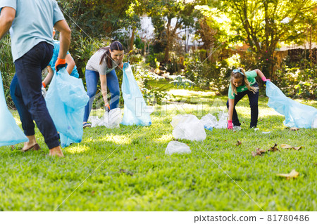 Caucasian parents, son and daughter putting rubbish in refuse sacks in the countryside 81780486