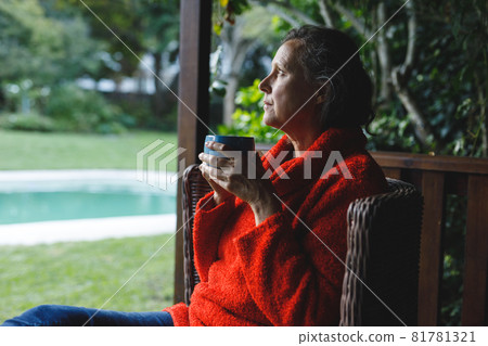 Happy senior caucasian woman sitting on chair, drinking coffee in garden Happy senior caucasian woman sitting on chair, drinking coffee in garden 81781321