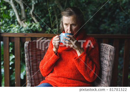 Thoughtful senior caucasian woman sitting on chair, drinking coffee in garden Thoughtful senior caucasian woman sitting on chair, drinking coffee in garden 81781322