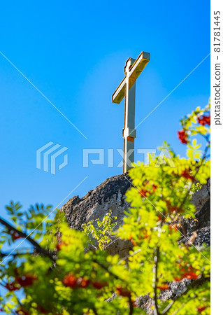 a gilded peasant Orthodox cross stands on top of a cliff 81781445