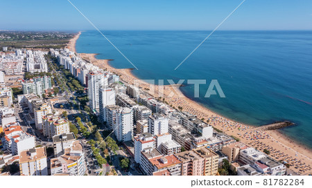 Beautiful aerial cityscapes of the tourist Portuguese city of Quarteira. On the seashore during the beach season with tourists who are sunbathing. 81782284