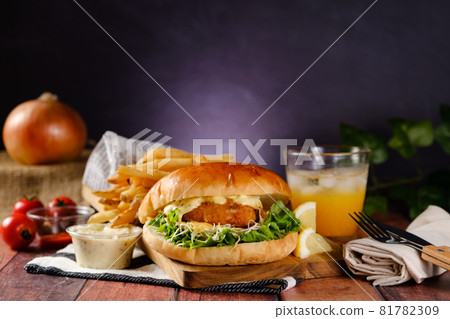A hearty fish burger set with tartar sauce, fries and juice 81782309