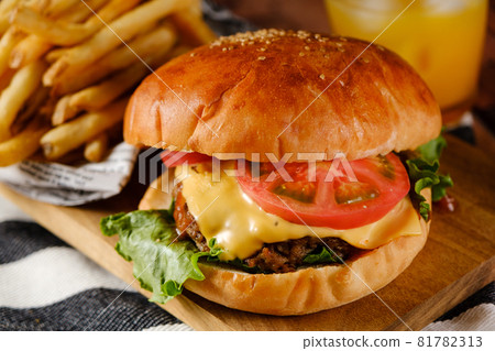 A hearty gourmet burger set with cheese, tomato, lettuce, fries and juice 81782313